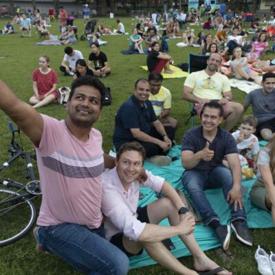 Audience members take a selfie with their group on the lawn of the Hatch Shell.